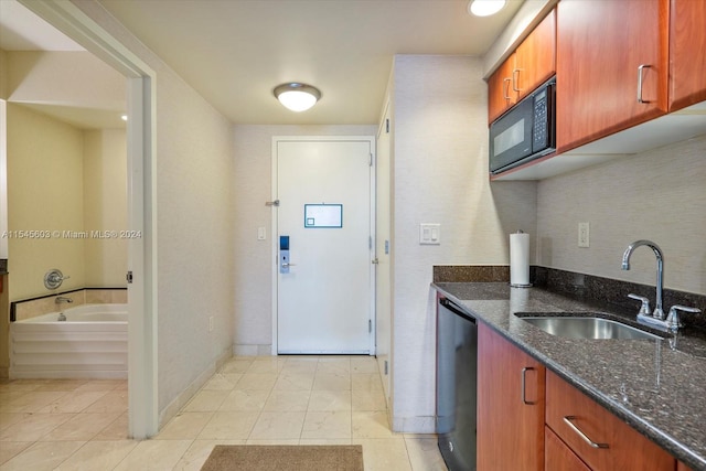 kitchen featuring light tile flooring, black microwave, dark stone countertops, dishwasher, and sink