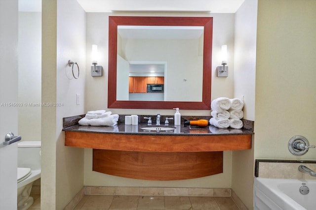 bathroom with a tub, tile flooring, oversized vanity, and toilet