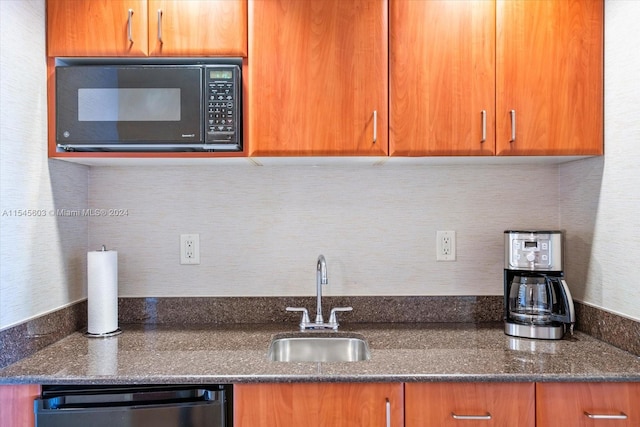 kitchen with dishwashing machine, dark stone countertops, and sink