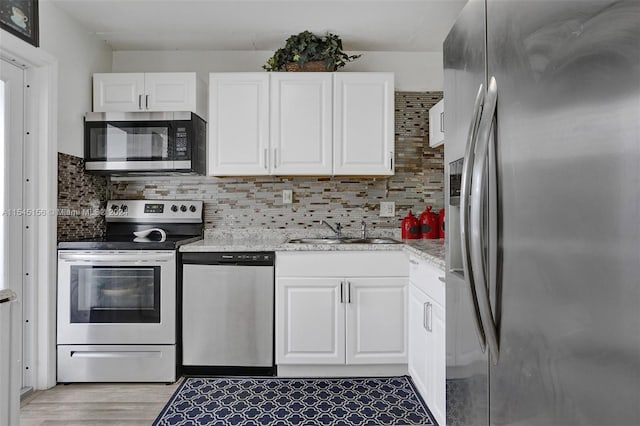 kitchen with tasteful backsplash, sink, white cabinetry, stainless steel appliances, and light stone counters