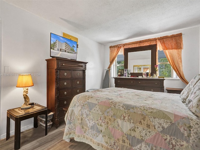 bedroom featuring multiple windows, hardwood / wood-style floors, and a textured ceiling