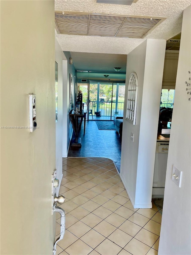 hallway with a textured ceiling and light tile floors