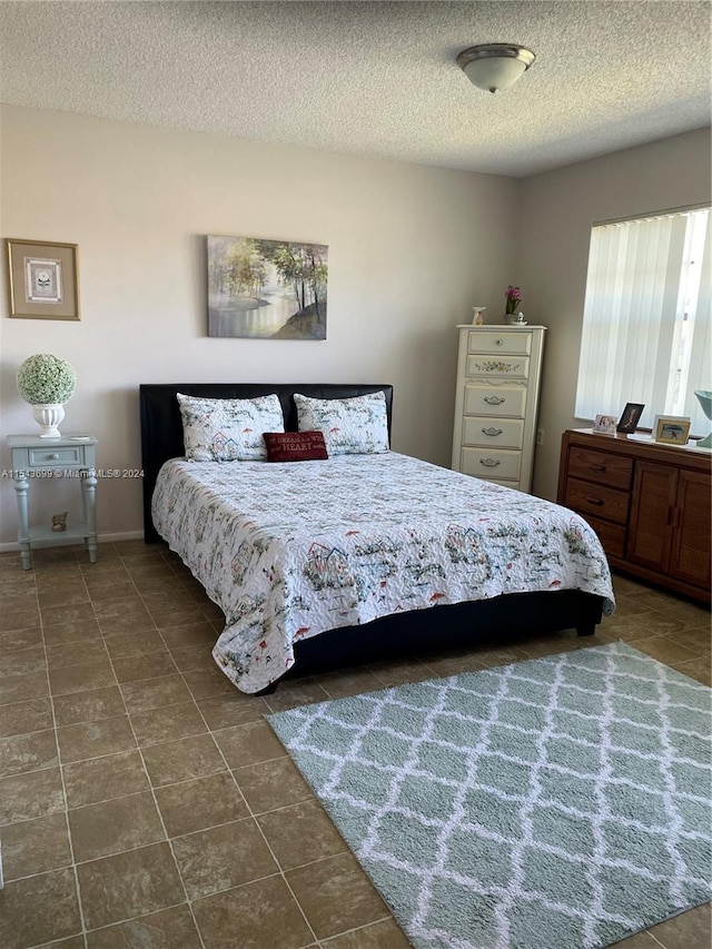 bedroom featuring dark tile floors and a textured ceiling