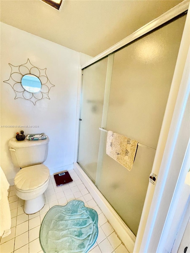 bathroom with tile floors, a shower with door, and toilet