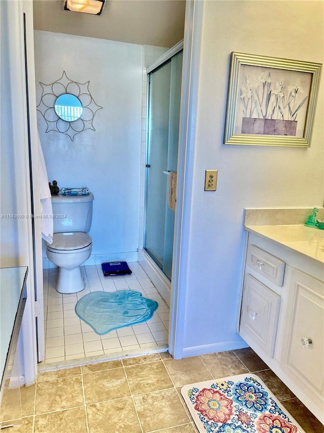 bathroom with tile floors, a shower with shower door, toilet, and vanity