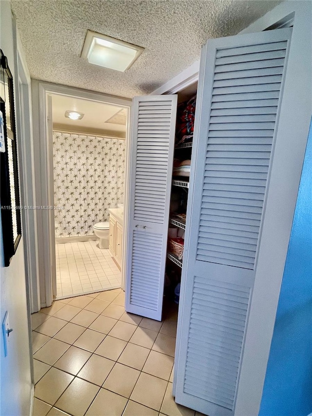 corridor featuring a textured ceiling and light tile flooring