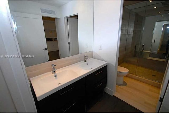 bathroom featuring an enclosed shower, hardwood / wood-style floors, toilet, and dual bowl vanity