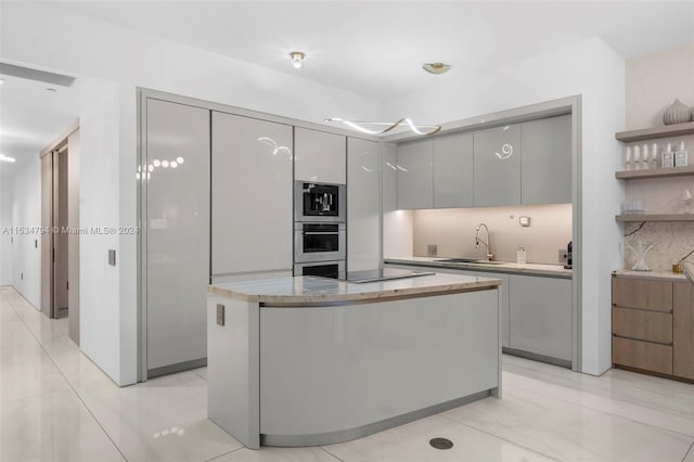 kitchen with decorative backsplash, stainless steel appliances, sink, gray cabinets, and a kitchen island