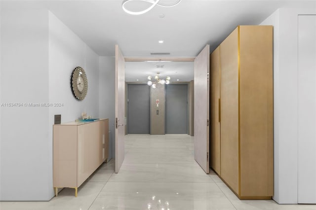 hallway featuring light tile patterned floors and an inviting chandelier