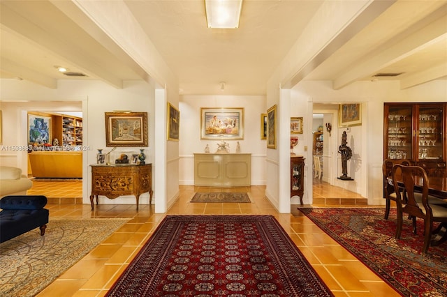 tiled foyer featuring beamed ceiling