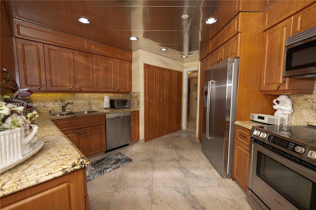 kitchen featuring light stone counters, stainless steel appliances, sink, and backsplash