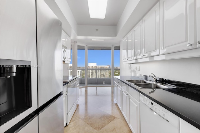 kitchen with white cabinetry, sink, floor to ceiling windows, and white appliances