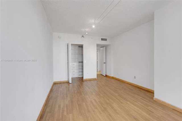 unfurnished bedroom featuring a textured ceiling, light wood-type flooring, and a closet