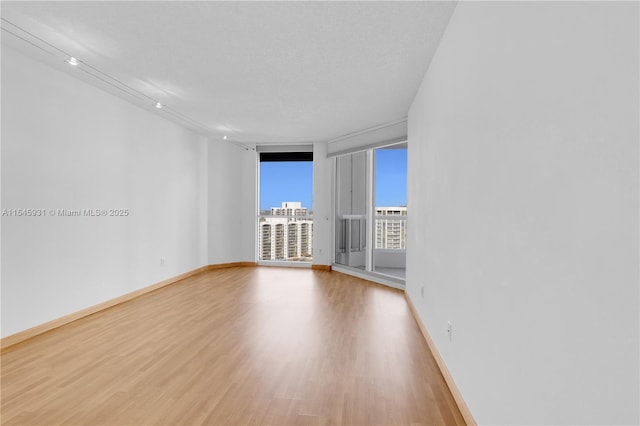 spare room featuring a textured ceiling and light hardwood / wood-style floors