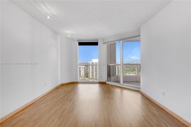 spare room with light hardwood / wood-style flooring, expansive windows, and a textured ceiling