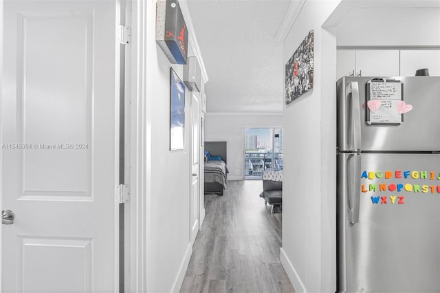 hallway with light hardwood / wood-style floors and a textured ceiling