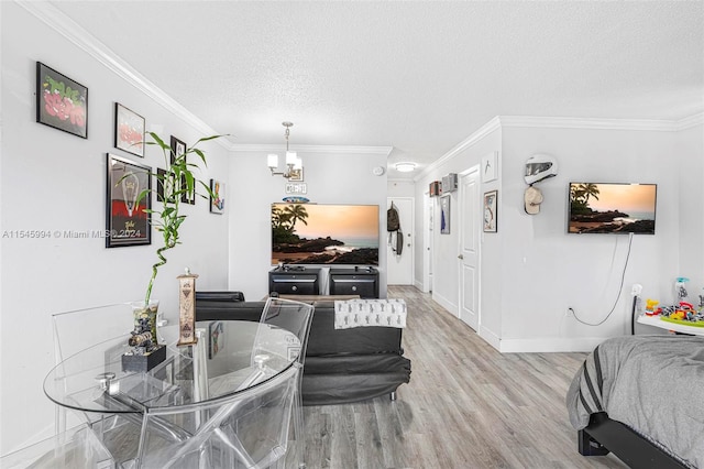 living room with a textured ceiling, ornamental molding, a chandelier, and light hardwood / wood-style floors