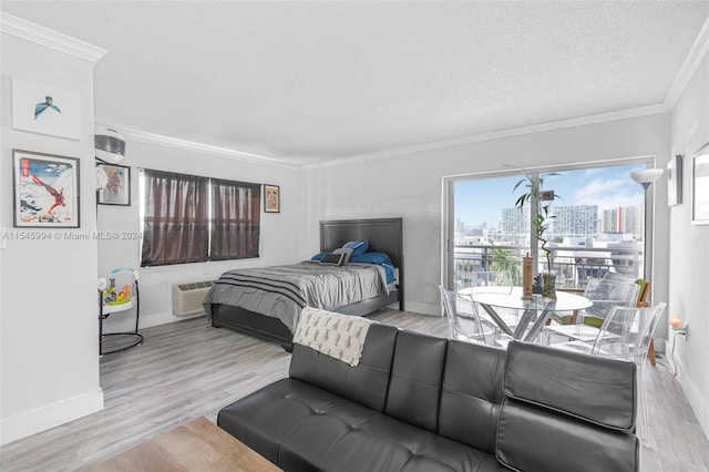 bedroom with a wall mounted AC, a textured ceiling, light hardwood / wood-style floors, access to outside, and ornamental molding