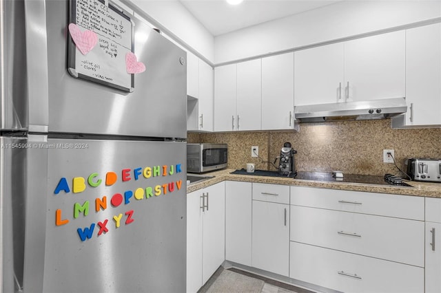 kitchen with stainless steel appliances, white cabinetry, and backsplash