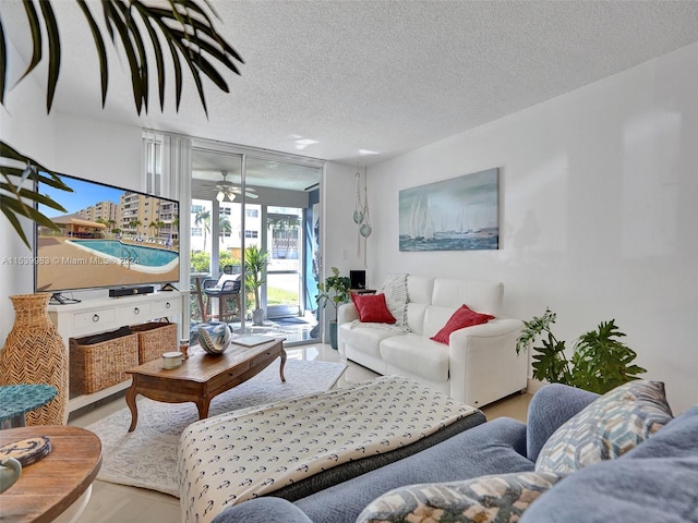 living room with ceiling fan, a textured ceiling, and light hardwood / wood-style flooring