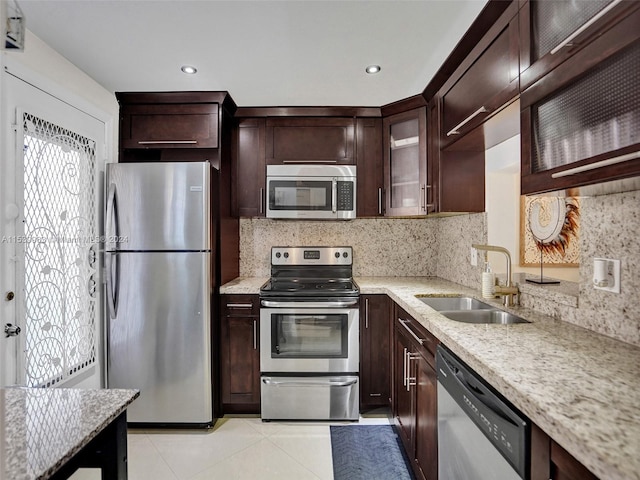 kitchen featuring light stone counters, backsplash, light tile patterned floors, stainless steel appliances, and sink