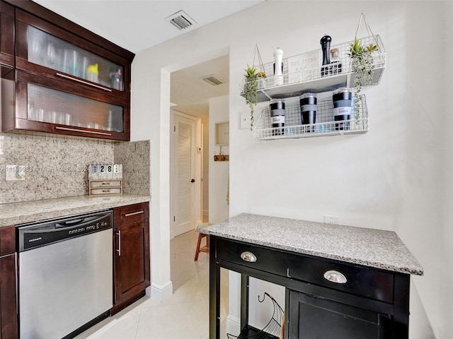 kitchen featuring light stone countertops, backsplash, light tile patterned floors, and stainless steel dishwasher