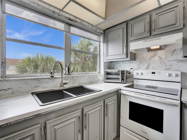 kitchen with light stone countertops, electric range, sink, tasteful backsplash, and gray cabinets