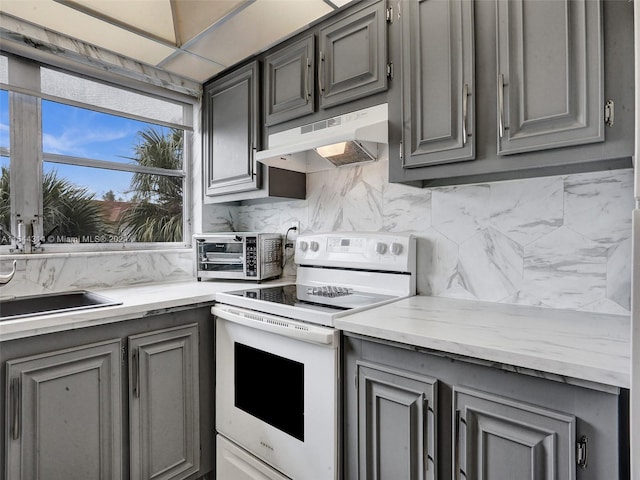 kitchen featuring premium range hood, white range with electric cooktop, light stone countertops, tasteful backsplash, and gray cabinetry