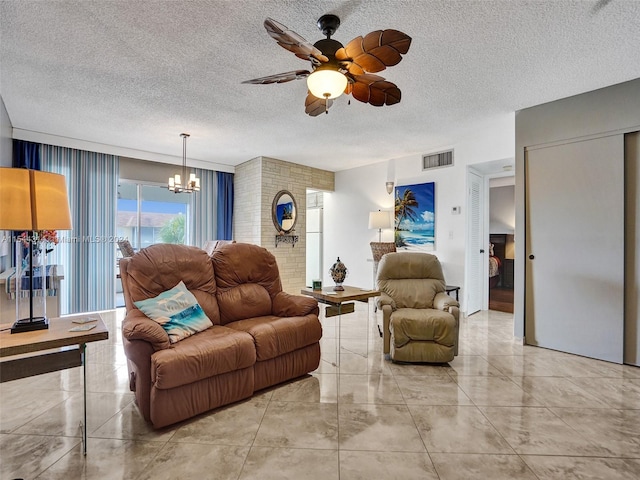 tiled living room featuring a textured ceiling and ceiling fan with notable chandelier