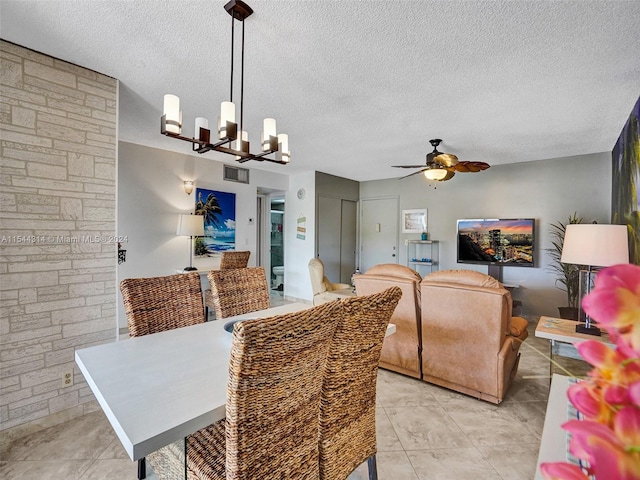 tiled dining area with a textured ceiling and ceiling fan with notable chandelier