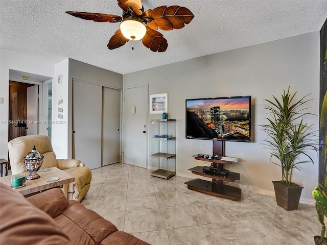 living room featuring a textured ceiling, light tile flooring, and ceiling fan