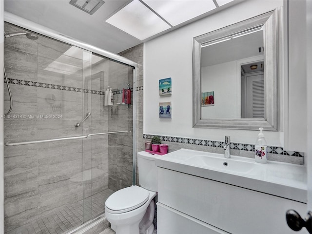 bathroom with toilet, a shower with door, and vanity with extensive cabinet space