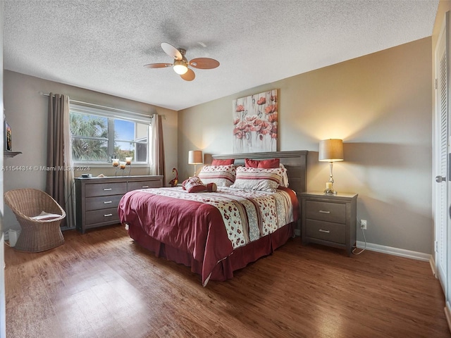 bedroom with a textured ceiling, ceiling fan, and dark hardwood / wood-style floors