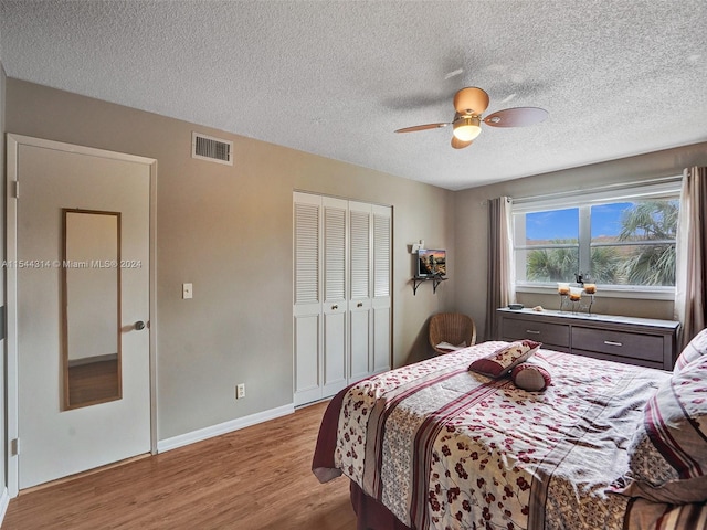 bedroom with a textured ceiling, dark hardwood / wood-style flooring, a closet, and ceiling fan