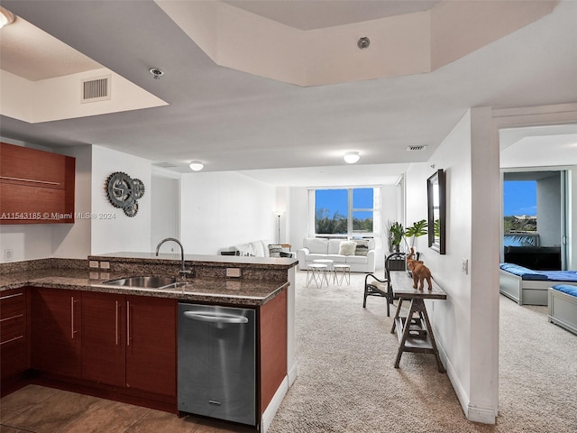 kitchen featuring light colored carpet, stainless steel dishwasher, dark stone countertops, and sink