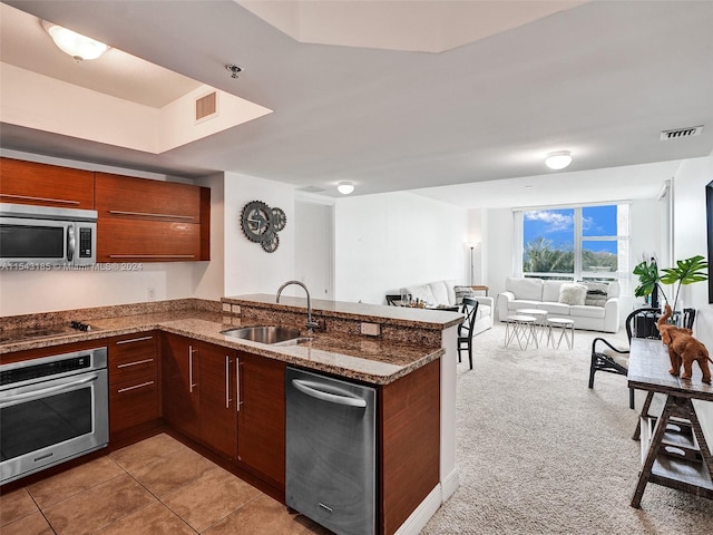 kitchen featuring kitchen peninsula, appliances with stainless steel finishes, sink, dark stone counters, and light colored carpet