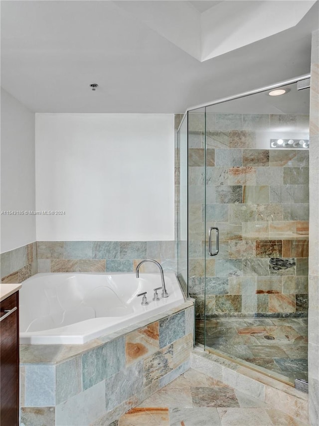 bathroom with tile flooring, separate shower and tub, and vanity