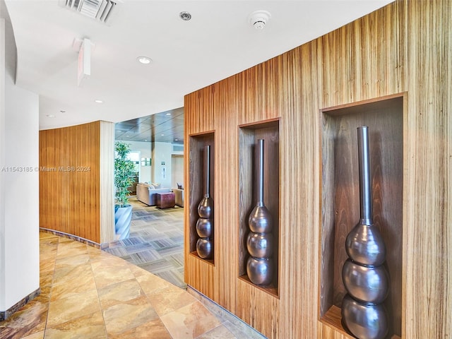 corridor featuring wood walls and light tile floors