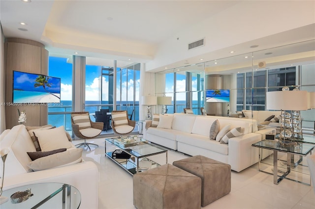 living room with a wall of windows, a water view, and light tile patterned floors