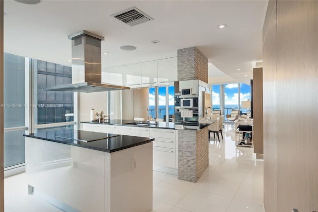 kitchen featuring black electric stovetop, white cabinets, sink, a kitchen island, and island range hood