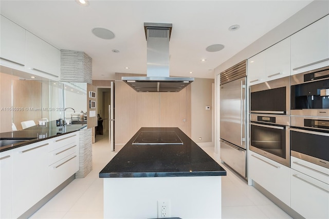 kitchen featuring white cabinets, stainless steel appliances, a center island with sink, and island exhaust hood