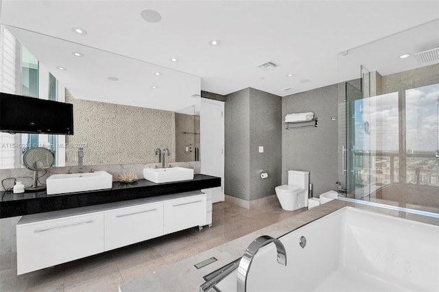 full bathroom featuring plus walk in shower, toilet, double sink vanity, and tile patterned flooring