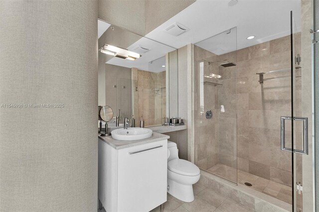 bathroom featuring tile patterned floors, vanity, a shower with shower door, and toilet