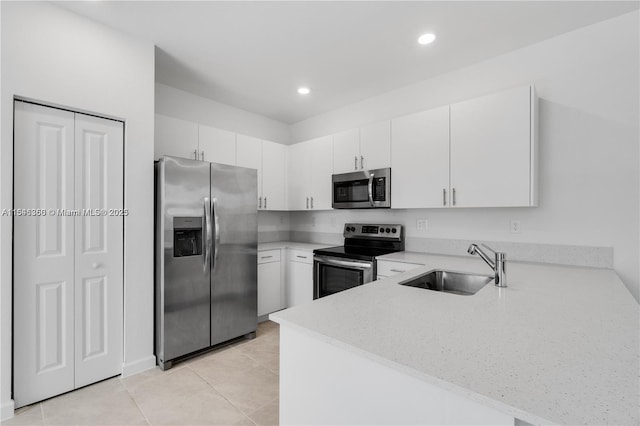 kitchen with white cabinets, appliances with stainless steel finishes, light tile patterned floors, and sink