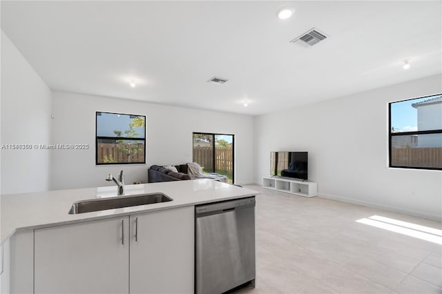 kitchen featuring light tile patterned floors, white cabinetry, stainless steel dishwasher, and sink