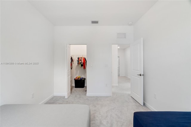 bedroom featuring a spacious closet, a closet, and light carpet