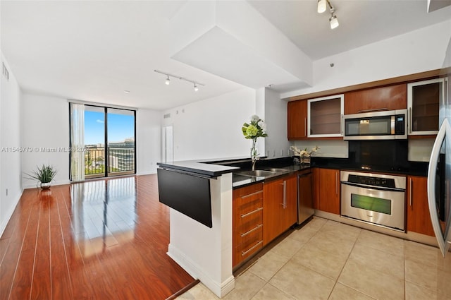 kitchen with appliances with stainless steel finishes, light tile floors, sink, rail lighting, and floor to ceiling windows