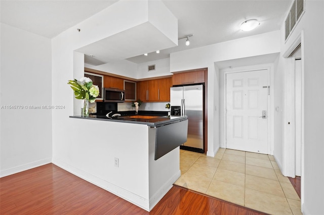 kitchen with light tile flooring, kitchen peninsula, and stainless steel appliances