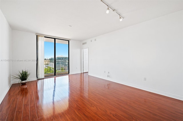 spare room featuring floor to ceiling windows, track lighting, and dark wood-type flooring