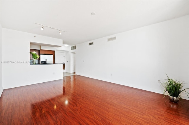 unfurnished living room featuring wood-type flooring and rail lighting